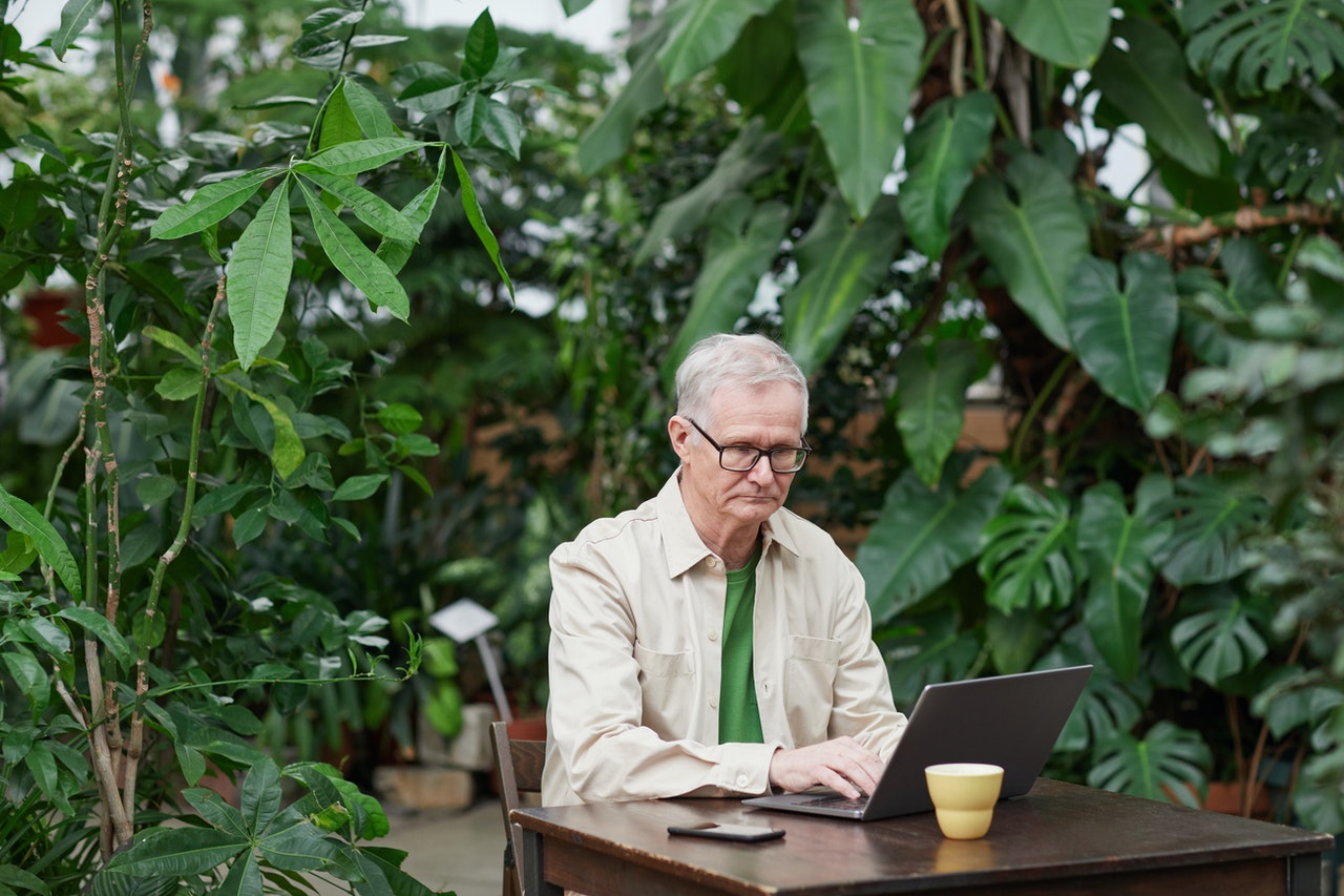 Older man using a laptop outside