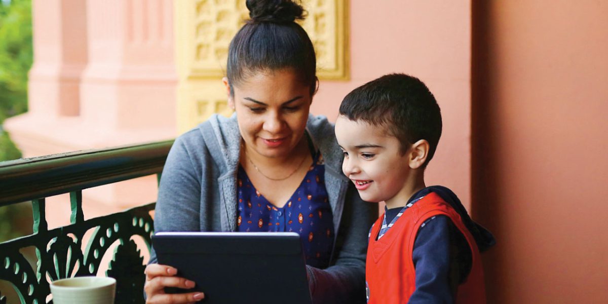 An indigenous mother and child looking at a tablet device together